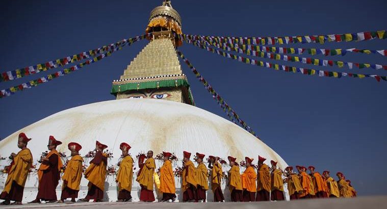 FILE- In this Nov. 20, 2016 file photo, Buddhist monks circle around the Boudhanath Stupa during during the final day of its purification ceremony in Kathmandu, Nepal. A year and a half after a colossal earthquake destroyed hundreds of its treasured historic sites, Nepal on Tuesday celebrated the restoration of the iconic Buddhist monument topped in gold that towers above Kathmandu. (AP Photo/Niranjan Shrestha, File)