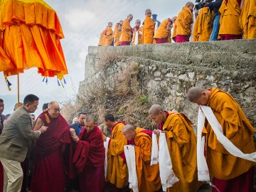 Tibetan Buddhist monks holding ceremonial scarfs stand in a line to welcome their spiritual leader the Dalai Lama, fourth left, as he arrives at the Jhonang Takten Phuntsok Choeling monastery in Shimla, India, Tuesday, March 18, 2014. (AP Photo/Tenzin Choejor)