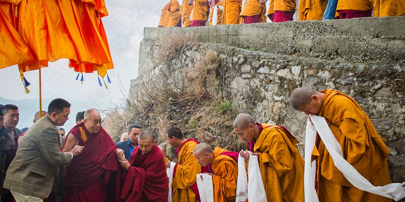 Tibetan Buddhist monks holding ceremonial scarfs stand in a line to welcome their spiritual leader the Dalai Lama, fourth left, as he arrives at the Jhonang Takten Phuntsok Choeling monastery in Shimla, India, Tuesday, March 18, 2014. (AP Photo/Tenzin Choejor)