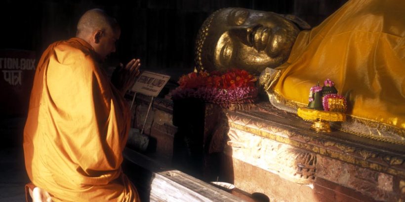 Statue of the `death of Buddha` with a monk praying - parinirvana - at Kusingara India